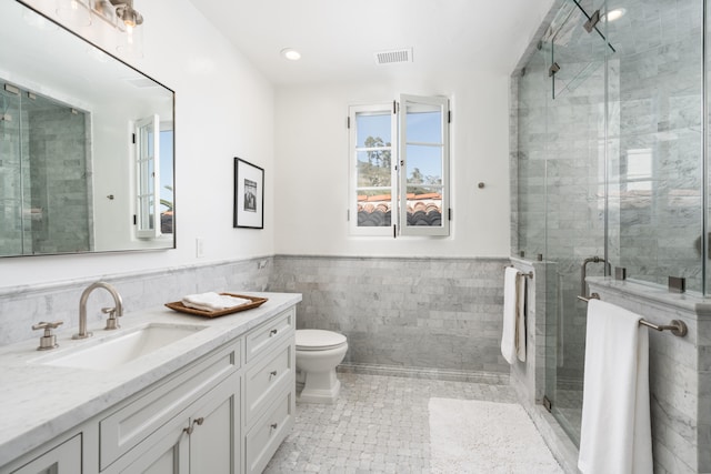 bathroom with tile walls, toilet, tile flooring, walk in shower, and vanity