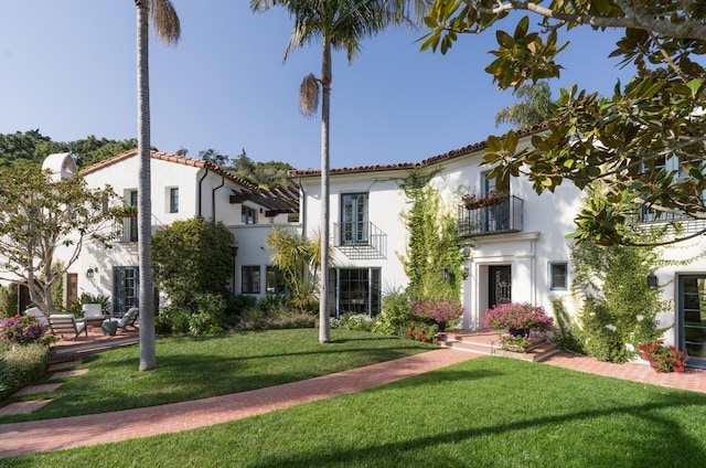 mediterranean / spanish house featuring a front lawn and a balcony