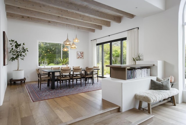 dining room with beam ceiling and light wood-style flooring