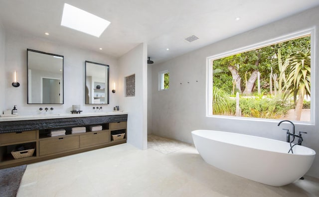 bathroom with a skylight, double vanity, a soaking tub, visible vents, and a walk in shower