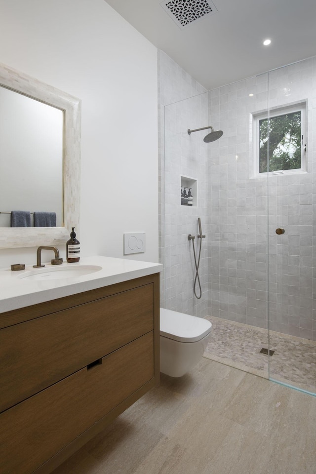 full bath with visible vents, toilet, wood finished floors, a tile shower, and vanity