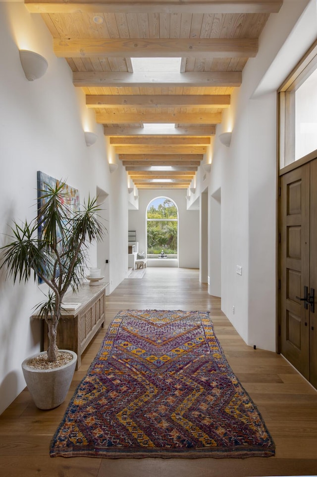 hall with wooden ceiling, light wood-type flooring, and beam ceiling