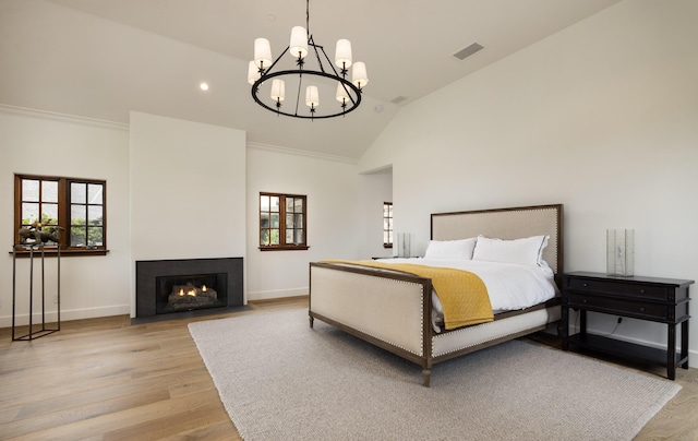 bedroom with a chandelier, lofted ceiling, and light hardwood / wood-style flooring