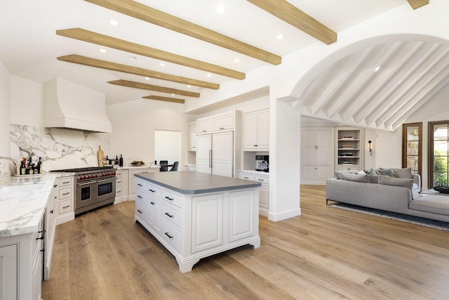 kitchen featuring a center island, high end appliances, decorative backsplash, custom range hood, and white cabinetry