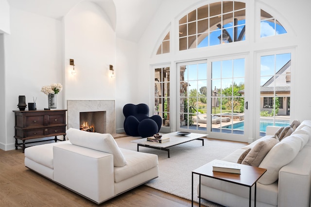 living room featuring wood-type flooring, a high ceiling, and a premium fireplace