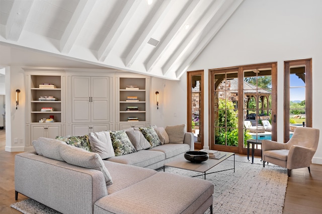 living room with beamed ceiling, built in shelves, light hardwood / wood-style floors, and high vaulted ceiling