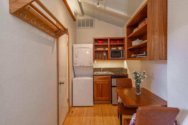 kitchen with stainless steel microwave, lofted ceiling with beams, sink, stacked washer / drying machine, and light hardwood / wood-style flooring