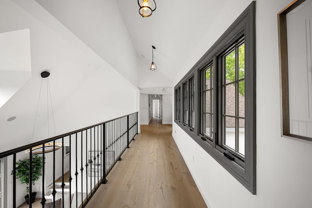 corridor with high vaulted ceiling and light hardwood / wood-style floors