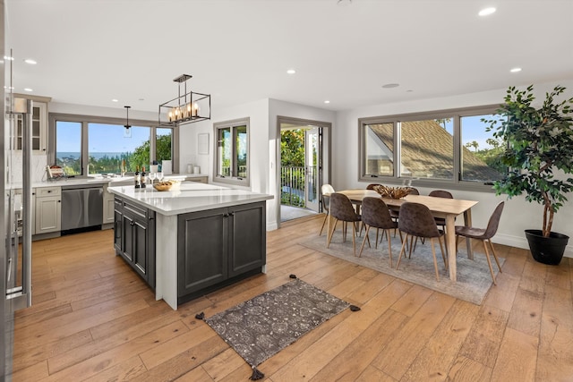 kitchen featuring decorative light fixtures, gray cabinetry, a center island, stainless steel dishwasher, and light hardwood / wood-style flooring