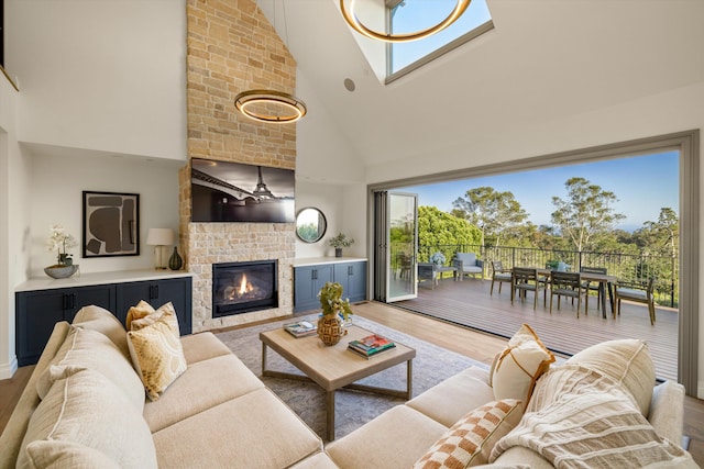 living room with a brick fireplace, hardwood / wood-style flooring, high vaulted ceiling, and ceiling fan