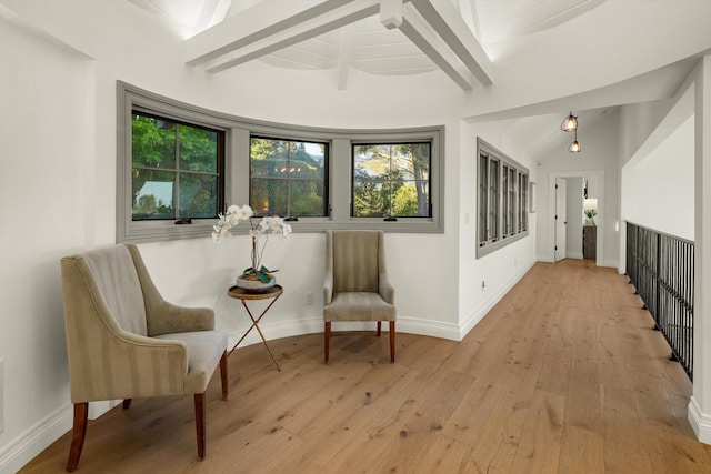 sitting room with vaulted ceiling with beams and light wood-type flooring