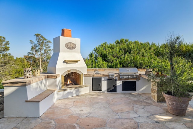 view of patio / terrace with area for grilling, exterior fireplace, and a grill