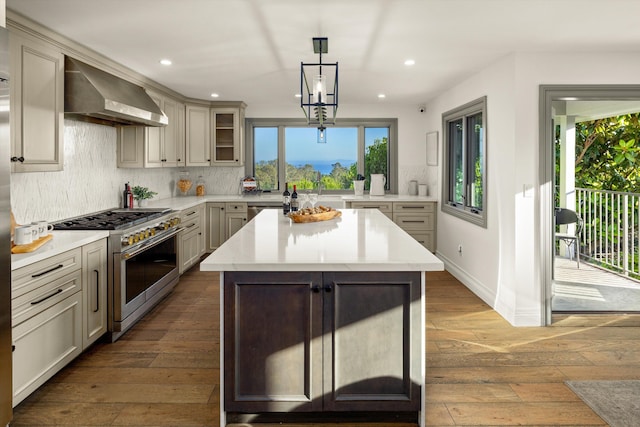 kitchen featuring wall chimney exhaust hood, tasteful backsplash, decorative light fixtures, appliances with stainless steel finishes, and a kitchen island