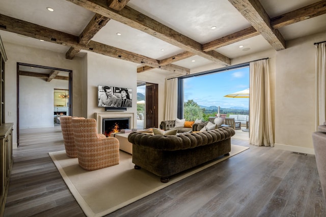 living area featuring baseboards, coffered ceiling, wood finished floors, a lit fireplace, and beam ceiling