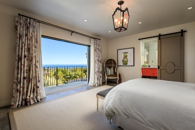 bedroom featuring ensuite bathroom, a barn door, recessed lighting, a water view, and access to outside