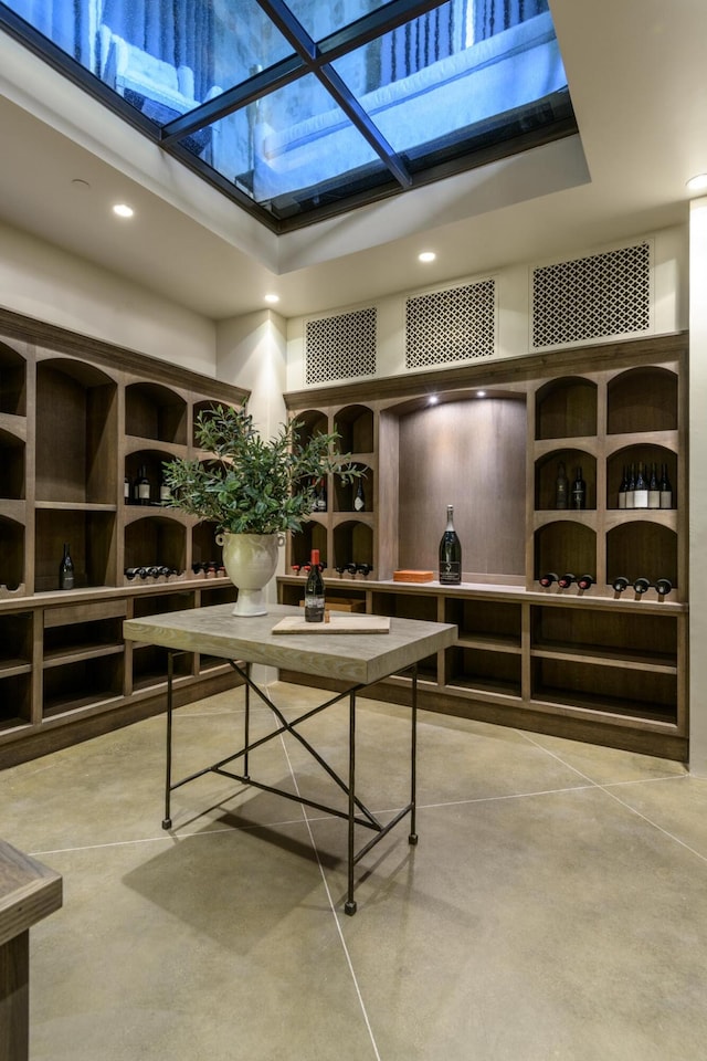 wine area featuring a towering ceiling, concrete flooring, and recessed lighting