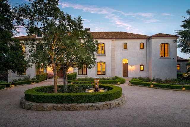 mediterranean / spanish home with curved driveway and stucco siding