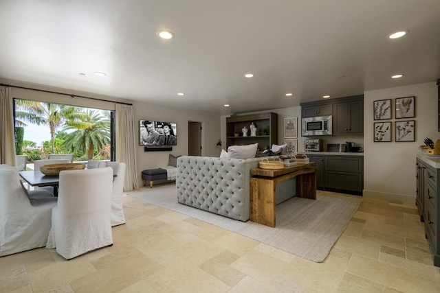 living area with baseboards, stone finish flooring, and recessed lighting