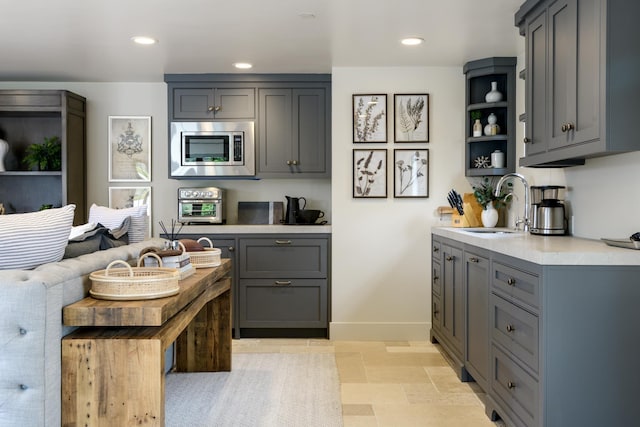 kitchen with recessed lighting, a sink, light countertops, gray cabinets, and stainless steel microwave