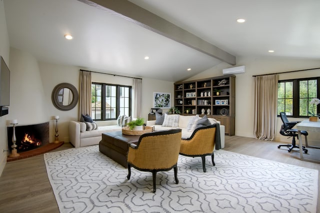 interior space featuring lofted ceiling with beams, light wood finished floors, a warm lit fireplace, and a wall unit AC