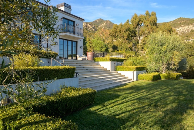 view of yard featuring stairs, a balcony, and a mountain view