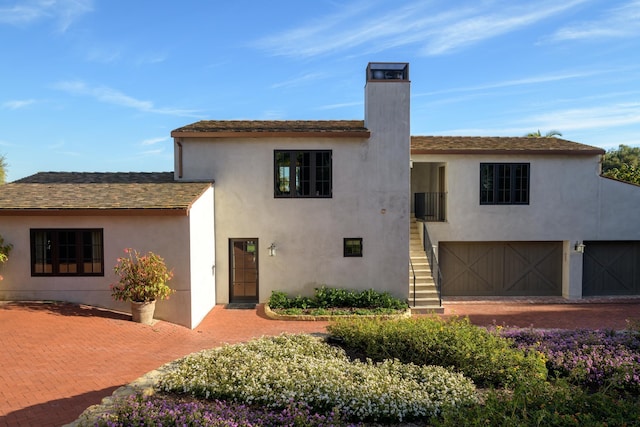 view of front of property featuring a garage, a chimney, stairway, and stucco siding