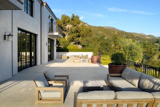 view of patio featuring outdoor lounge area, a balcony, and a mountain view