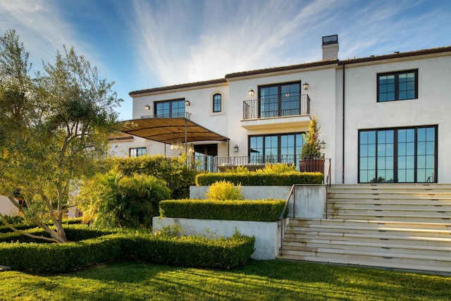 back of property with a yard, a chimney, and stucco siding