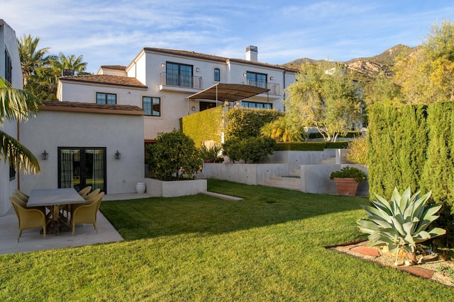 back of house featuring a patio, a lawn, a mountain view, and stucco siding