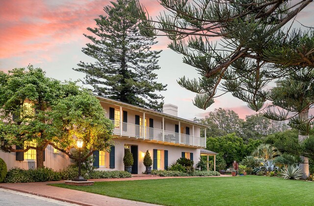 view of front facade featuring a balcony and a lawn