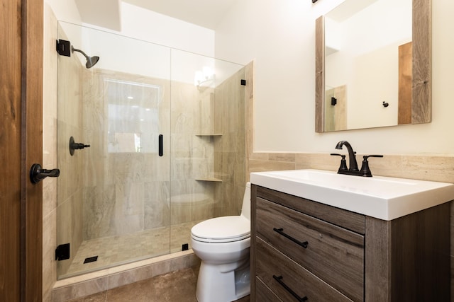 full bathroom featuring toilet, tile walls, wainscoting, vanity, and a stall shower