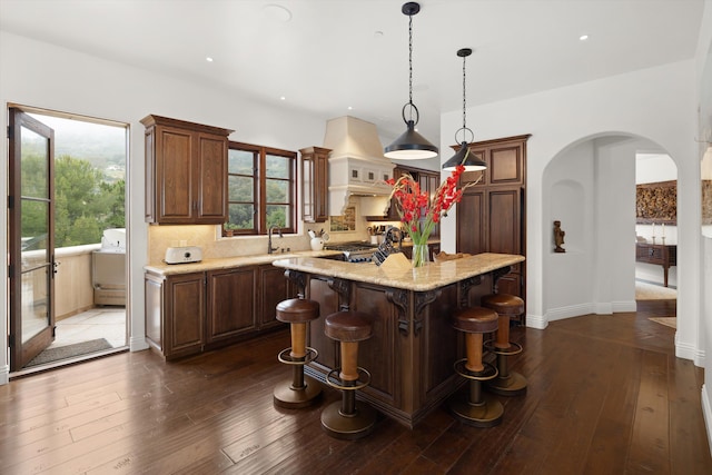 kitchen featuring a center island, sink, dark hardwood / wood-style floors, pendant lighting, and range