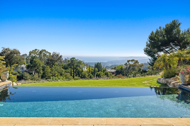 view of pool with a water view and a lawn