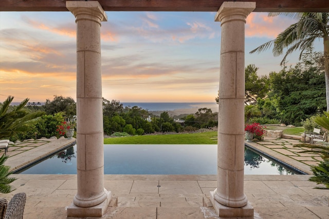 pool at dusk with a patio area