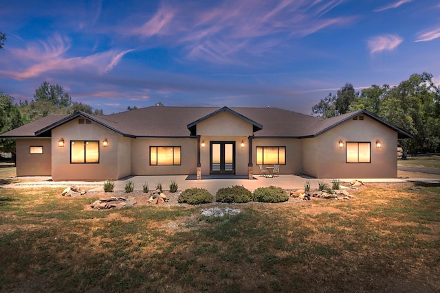 view of front of house featuring a lawn, a patio, and french doors