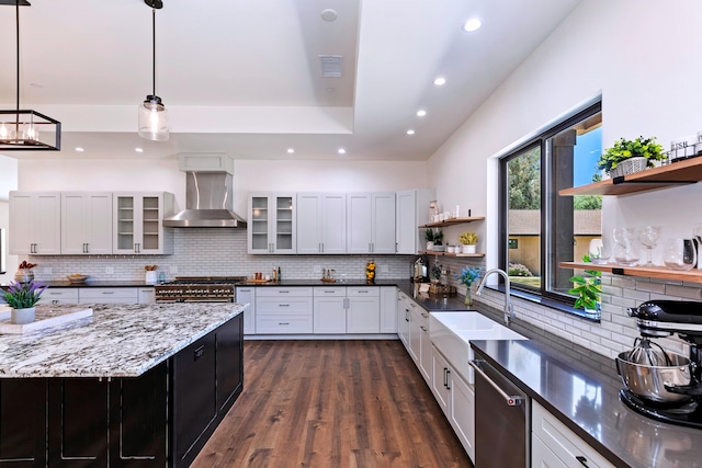 kitchen featuring pendant lighting, white cabinetry, wall chimney range hood, and backsplash