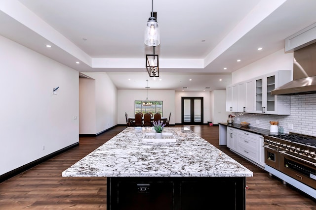 kitchen featuring white cabinets, decorative light fixtures, double oven range, and a kitchen island