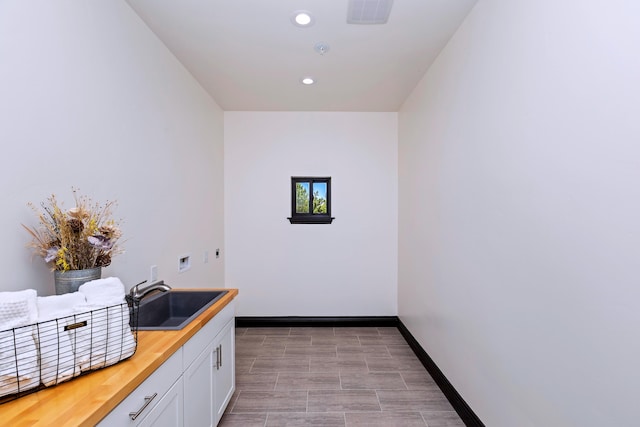 interior space featuring white cabinetry, butcher block counters, and sink