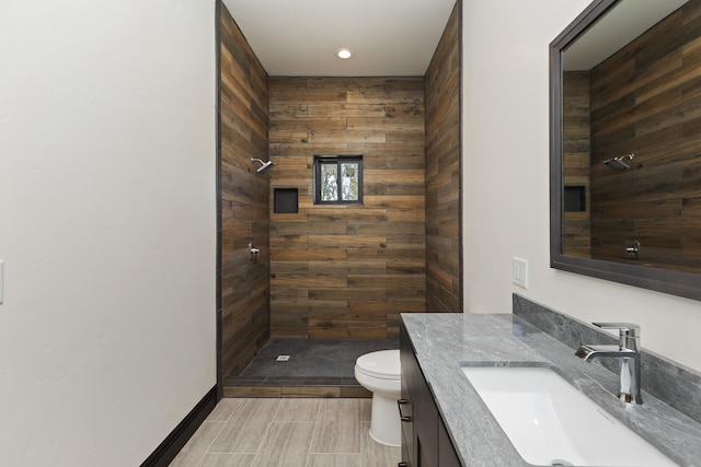 bathroom with tiled shower, vanity, and toilet