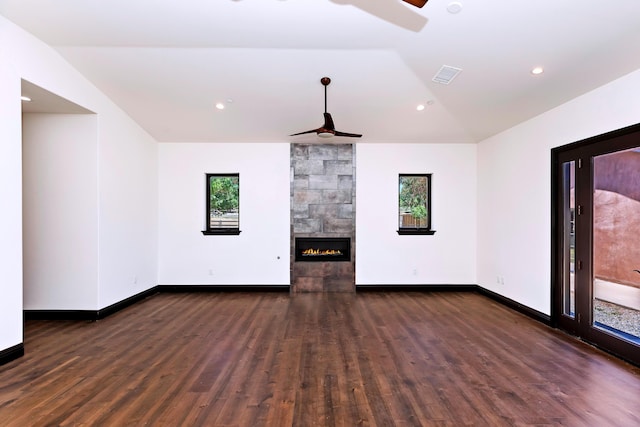 unfurnished living room with vaulted ceiling, a wealth of natural light, dark wood-type flooring, and a tiled fireplace