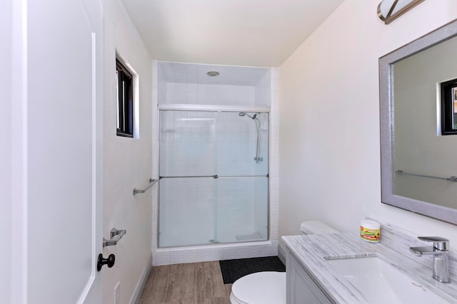 bathroom featuring vanity, wood-type flooring, a shower with shower door, and toilet