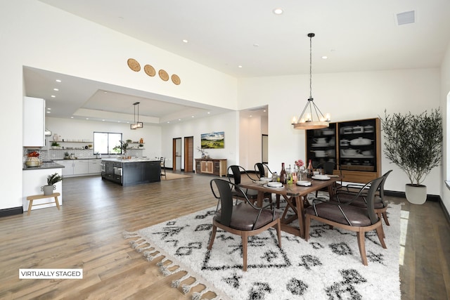 dining area featuring dark hardwood / wood-style floors, an inviting chandelier, and a tray ceiling