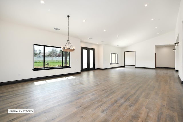 interior space featuring hardwood / wood-style floors, lofted ceiling, and an inviting chandelier