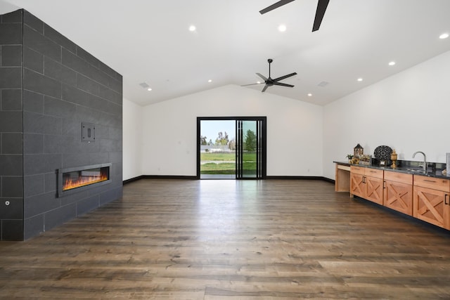 living room with a tile fireplace, dark hardwood / wood-style floors, lofted ceiling, and sink