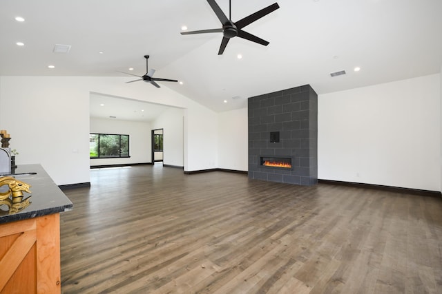 unfurnished living room with a tile fireplace, ceiling fan, sink, dark hardwood / wood-style floors, and lofted ceiling