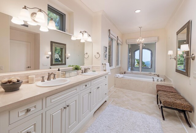 bathroom featuring a chandelier, a relaxing tiled bath, plenty of natural light, and double sink vanity