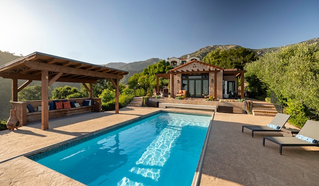 view of pool with a patio area, a pergola, an outdoor hangout area, and a mountain view