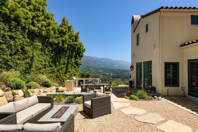 view of patio / terrace with a mountain view and an outdoor living space with a fire pit