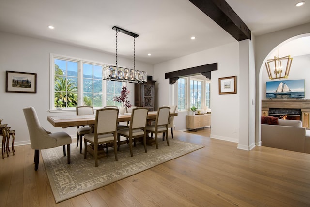 dining room with beamed ceiling, light wood-type flooring, and a premium fireplace