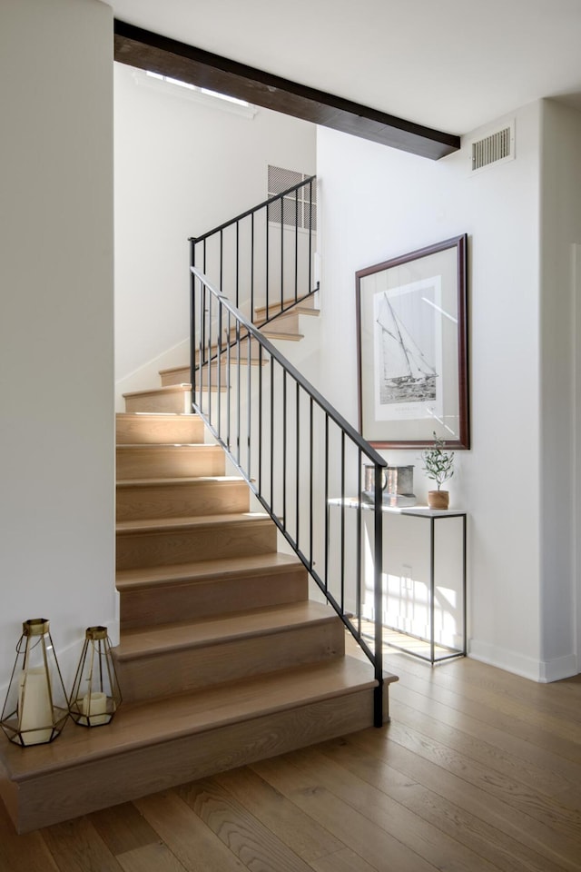 stairway with beamed ceiling and hardwood / wood-style flooring